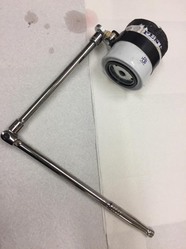 Secondary fuel filter removal tool with friction tape on filter. Note crushed filter.